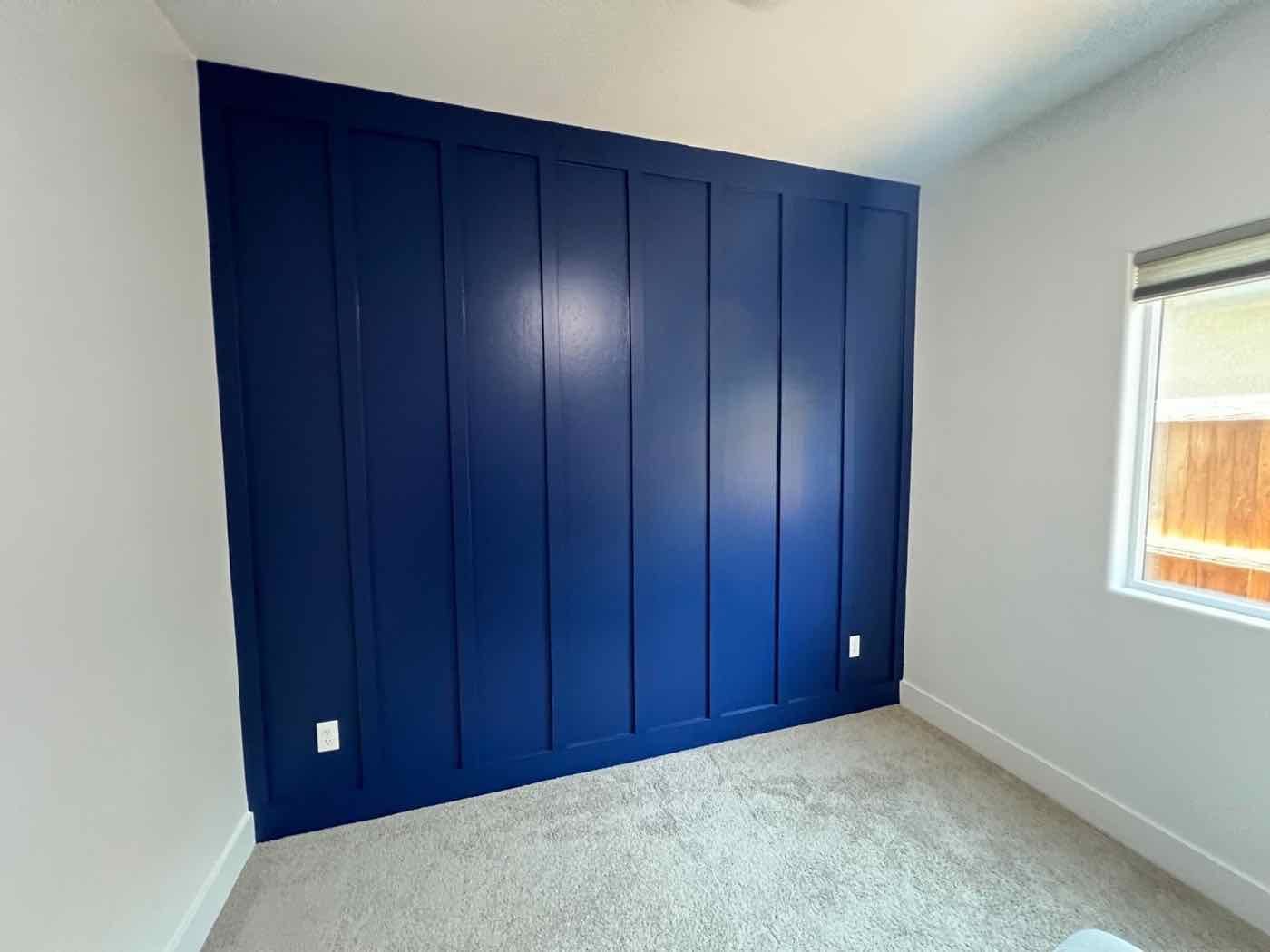 Bedroom with a navy blue board-and-batten accent wall, built and painted by Been Brothers