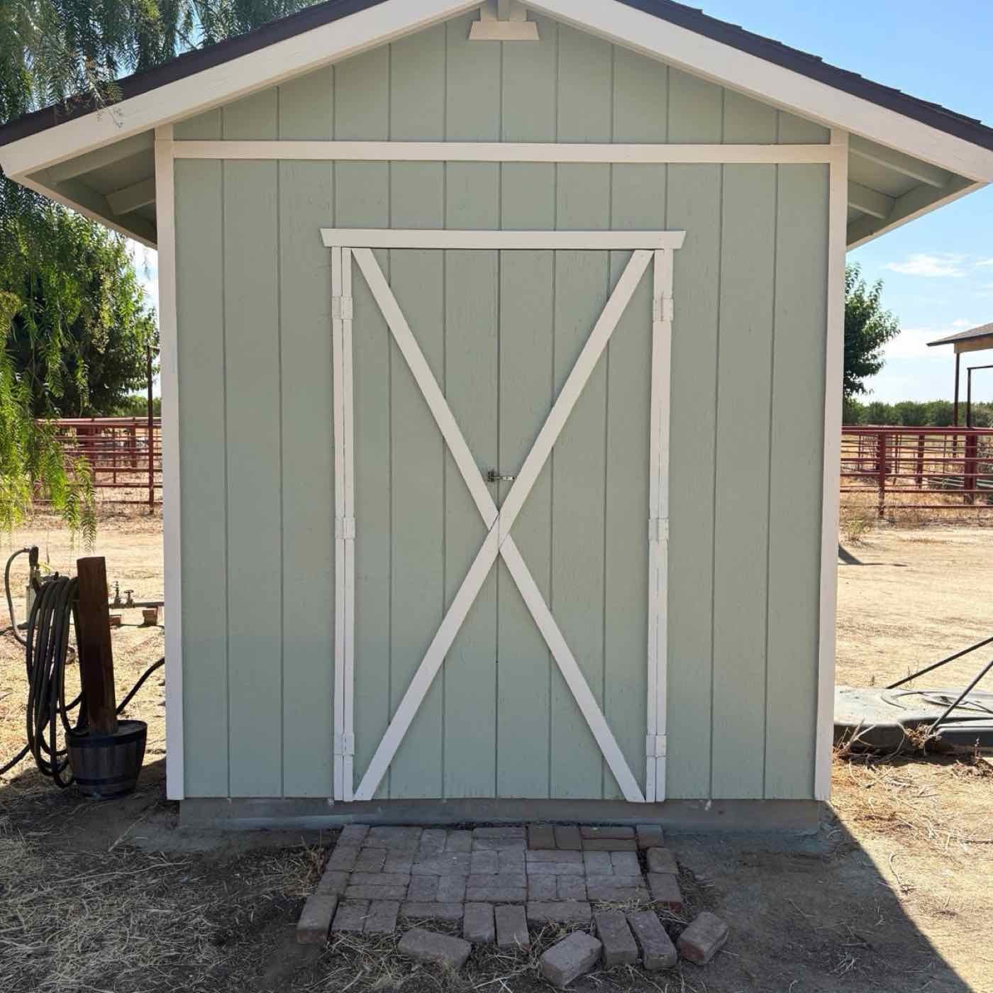 Storage shed after repainting: sage green siding with white trim